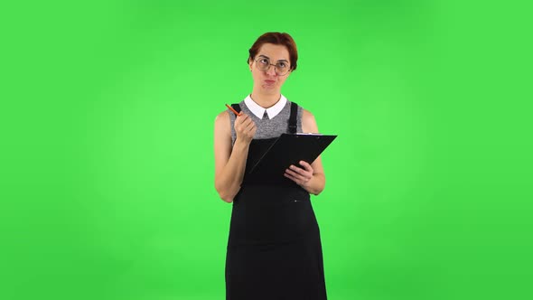 Funny Girl in Round Glasses Is Angrily Writing Plans at Black Folder with Pencil. Green Screen