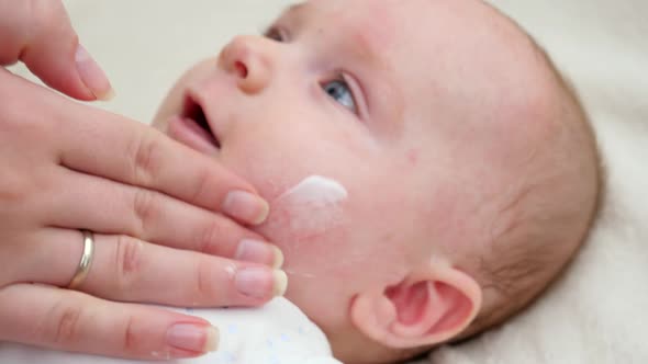 Closeup of Mother's Hand Applying Moisturizing Medical Lotion on Skin of Her Little Baby Suffering