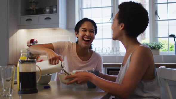 Mixed race lesbian couple preparing and eating breakfast in kitchen