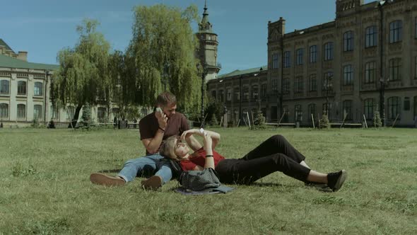 College Students Using Cellphones on Campus Lawn