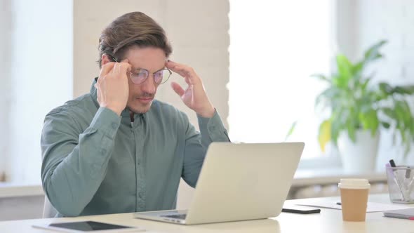 Middle Aged Man with Laptop having Headache