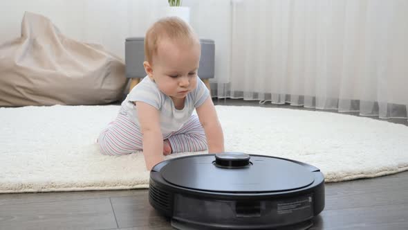 Cute Baby Boy Crawling on Floor and Looking on Robot Vacuum Cleaner