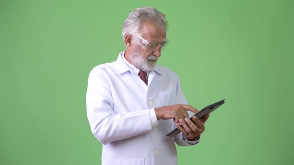 Handsome Senior Bearded Man Doctor Against Green Background