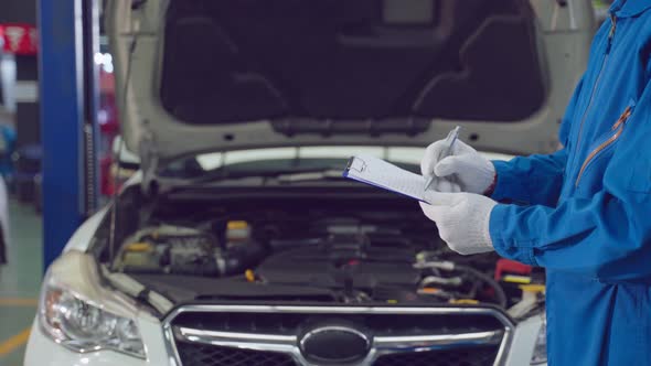 Asian automotive mechanic man hold checklist clipboard check up engine.