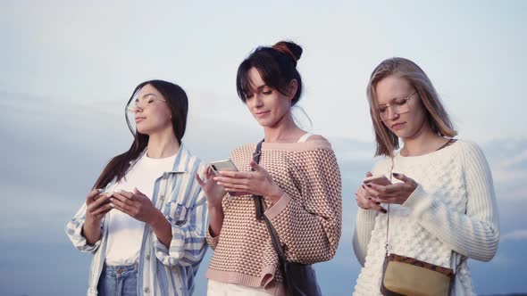 Three Ladies Texting in Their Smart Phones in the Street