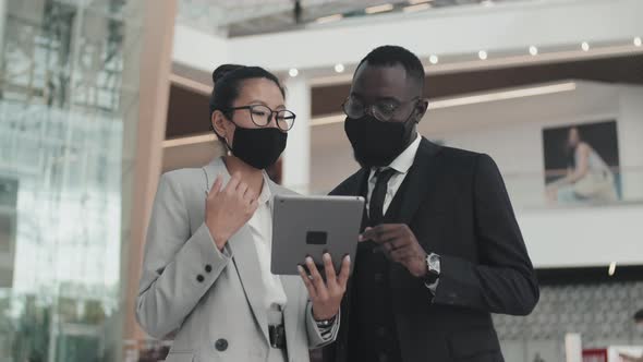 Businesspeople in Face Masks Using Tablet in Lobby