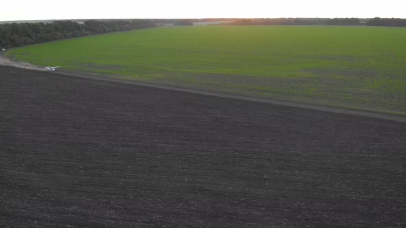 A Small Airplane Takes Off From a Field at Sunrise.