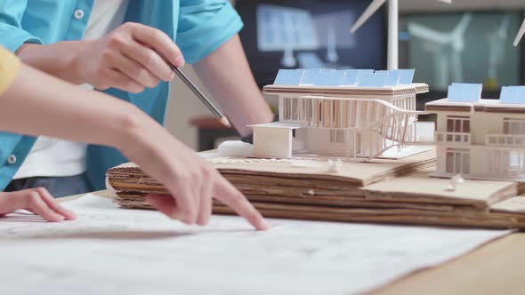 Close Up Of Man And Woman Helping Each Other Building The Model Of A Small House With Solar Panel