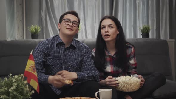 Young Caucasian Friends Man and Girl Watching Football Game on TV Together at Home. Couple Fan