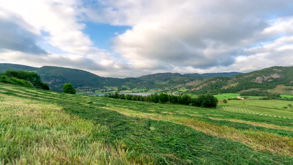 Daylight time lapse of clouds gliding over vast green landscape in countryside