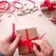 Man's hands wrap christmas present in craft paper with red ribbon and berries. - VideoHive Item for Sale
