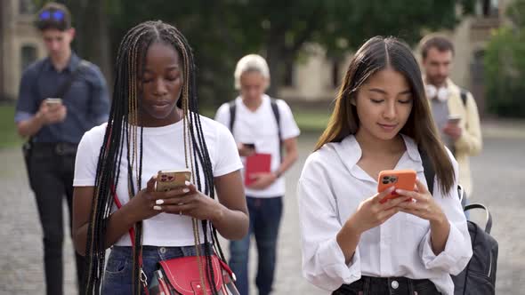 Multiracial Students Using Cellphones During Walk