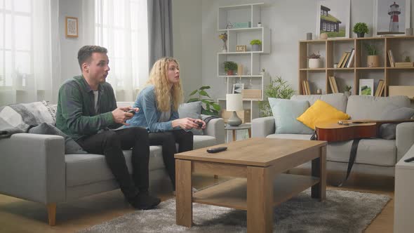 Young Man and Woman Have Fun Playing Together on a Console at Home