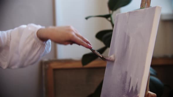 Young Woman Artist Drawing a Painting with Purple Colors