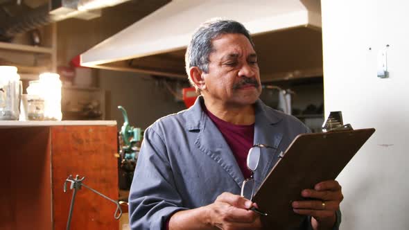 Shoemaker reading clipboard in workshop