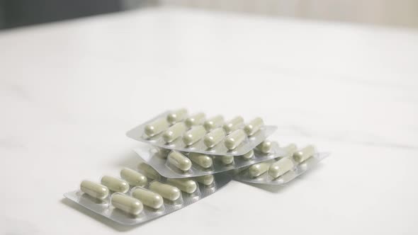 Person picking up various pills on a table. Medication addiction concept.