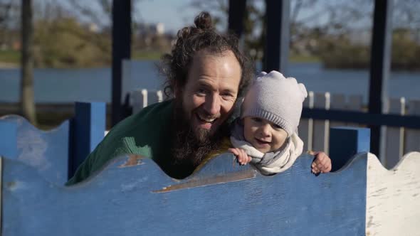 Father holding infant son in public playground, Zagreb, Croatia.