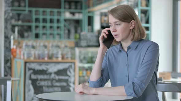 Young Woman Talking on Smartphone in Cafe