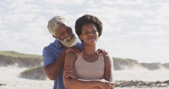 African american couple embracing and looking away on sunny beach