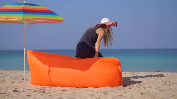 Young Woman on a Tropical Beach Laying Down on an Inflatable Sofa. Summer Vacation Concept