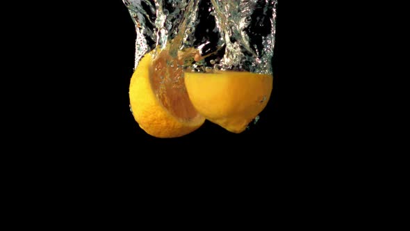 Super Slow Motion Two Halves of Lemon Fall Under the Water with Air Bubbles