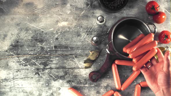 Super Slow Motion Man's Hand Puts Sausages in a Pan of Water for Cooking