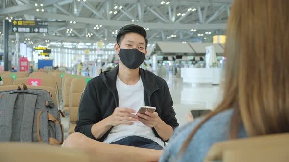friends asian tourist traveller wear protective face mask  have conversation wait flight schedule