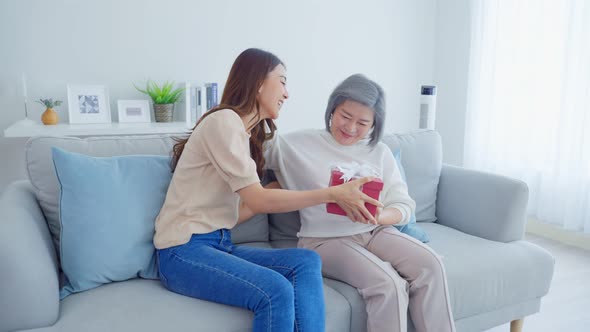Asian beautiful woman daughter surprise and give present box to her mother with birthday gift.