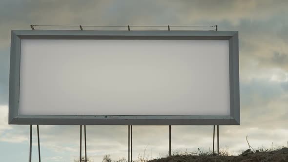 Blank White Billboard on the Background of the Sky with Moving Clouds in the Sunset Light