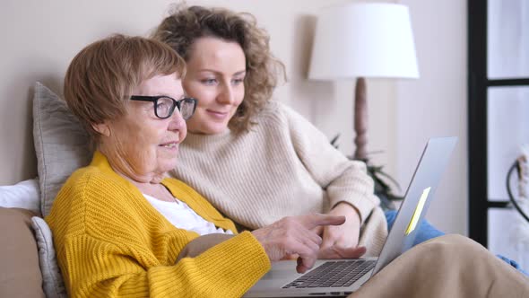 Grandmother And Granddaughter Using Laptop Computer Together At Home
