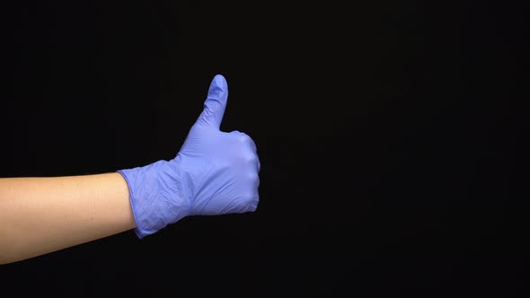 Female Hand in a Latex Medical Glove Makes an Like Gesture Isolated on Black Background