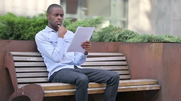 Pensive African Man Thinking While Reading Documents Outdoor