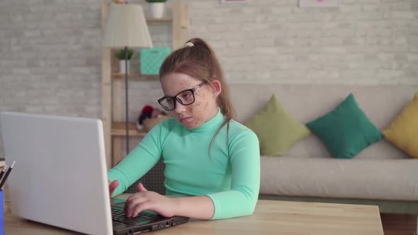 Portrait of a Teenage Girl with a Defect or Face Burn Using a Laptop or Computer