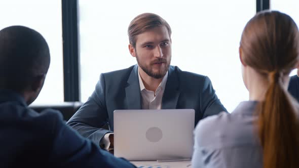 Young man in a suit talking with colleagues at a business meeting