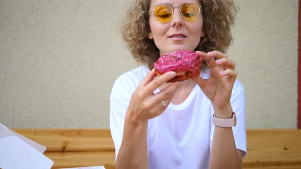 Attractive Blonde Woman Eating Pink Donut.