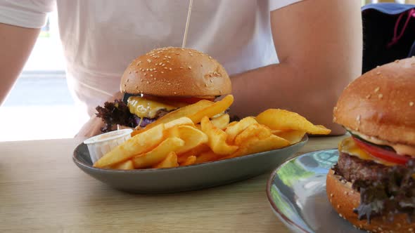 View on Rench Fries Next to a Huge Cheeseburger or Burger with a Cutlet Lettuce Cheese and Tomatoes