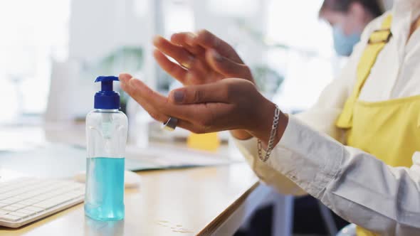 Mid section of woman sanitizing her hands at office