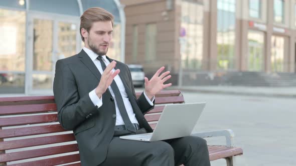 Businessman Talking on Video Call While Sitting Outdoor on Bench