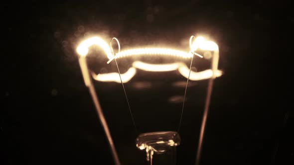 Tungsten Filament in a Glass Lamp Closeup in Slow Motion on Black Background