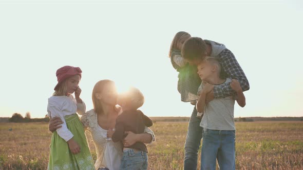 Happy Parents Kiss Their Children on a Sunset Background. The Large Family.