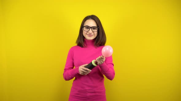 A Young Woman Inflates a Pink Balloon with a Pump and It Bursts on a Yellow Background. Girl in a