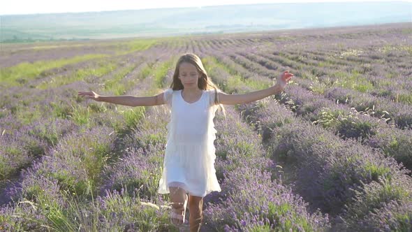 Woman in Lavender Flowers Field at Sunset in White Dress and Hat