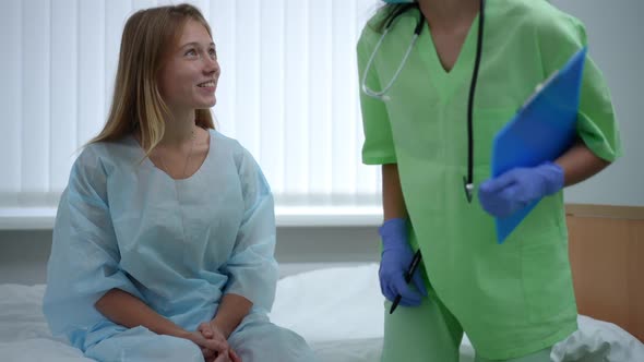 Teenage Girl Sitting on Bed in Hospital Ward As Doctor Entering Talking Smiling