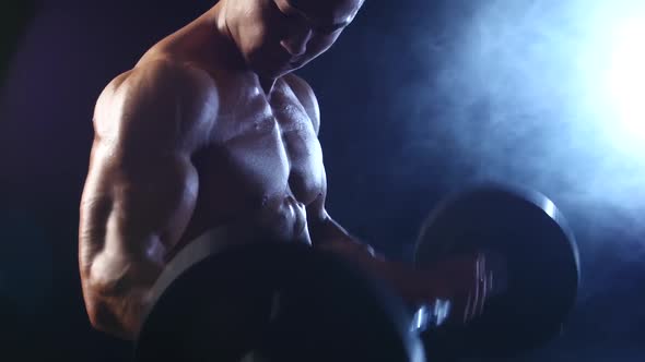 Bodybuilder Lifts a Barbell To Training Biceps, Black Smoke Background