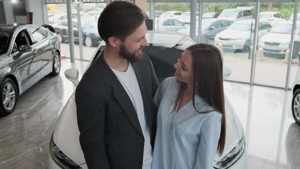 Visiting Car Dealership. Beautiful Couple Is Holding a Key of Their New Car, Looking at Camera and