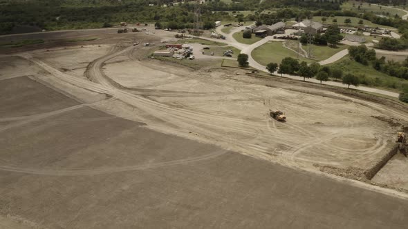 A dump truck follows the tracks made on a construction site with a front loader in the distance scoo