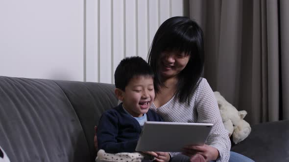 Asian Mother with Son Watching Movie on Tablet