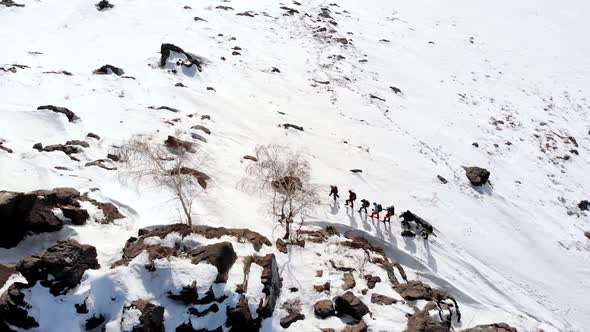 aerial quadrocopter removes the mountain, covered with snow, flying over it. Across which is a group