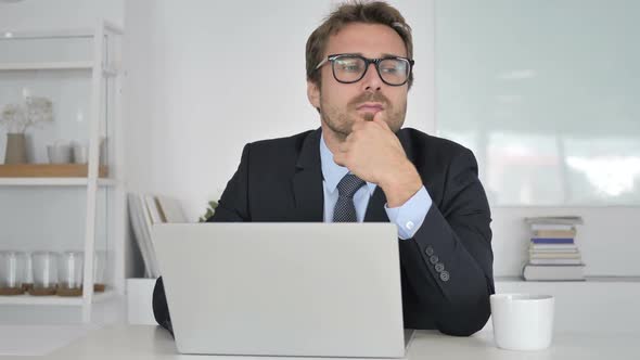 Pensive Businessman Thinking and Working on Laptop