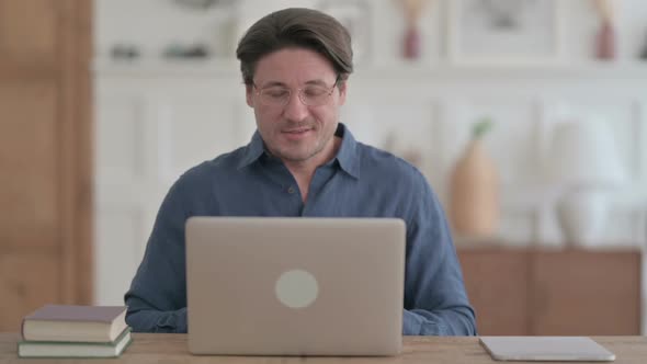 Young Man Talking on Video Call on Laptop in Office